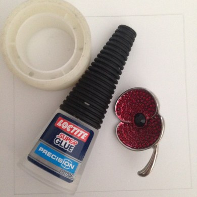 Objects: A small roll of tape, a small container of superglue, and a poppy brooch